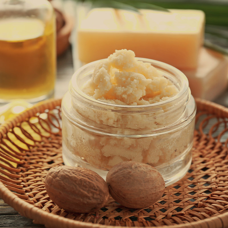 Raw shea nuts, a key ingredient in Guapo's natural skincare products, displayed alongside a jar of creamy shea nut butter.